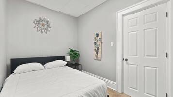 A bedroom with a bed, a nightstand, a wall-mounted flower decoration, and a door.