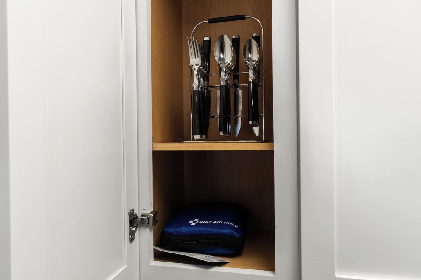 Un meuble contenant un ensemble de couteaux et un sac bleu étiqueté « PREMIERS SOINS UNIQUEMENT ».