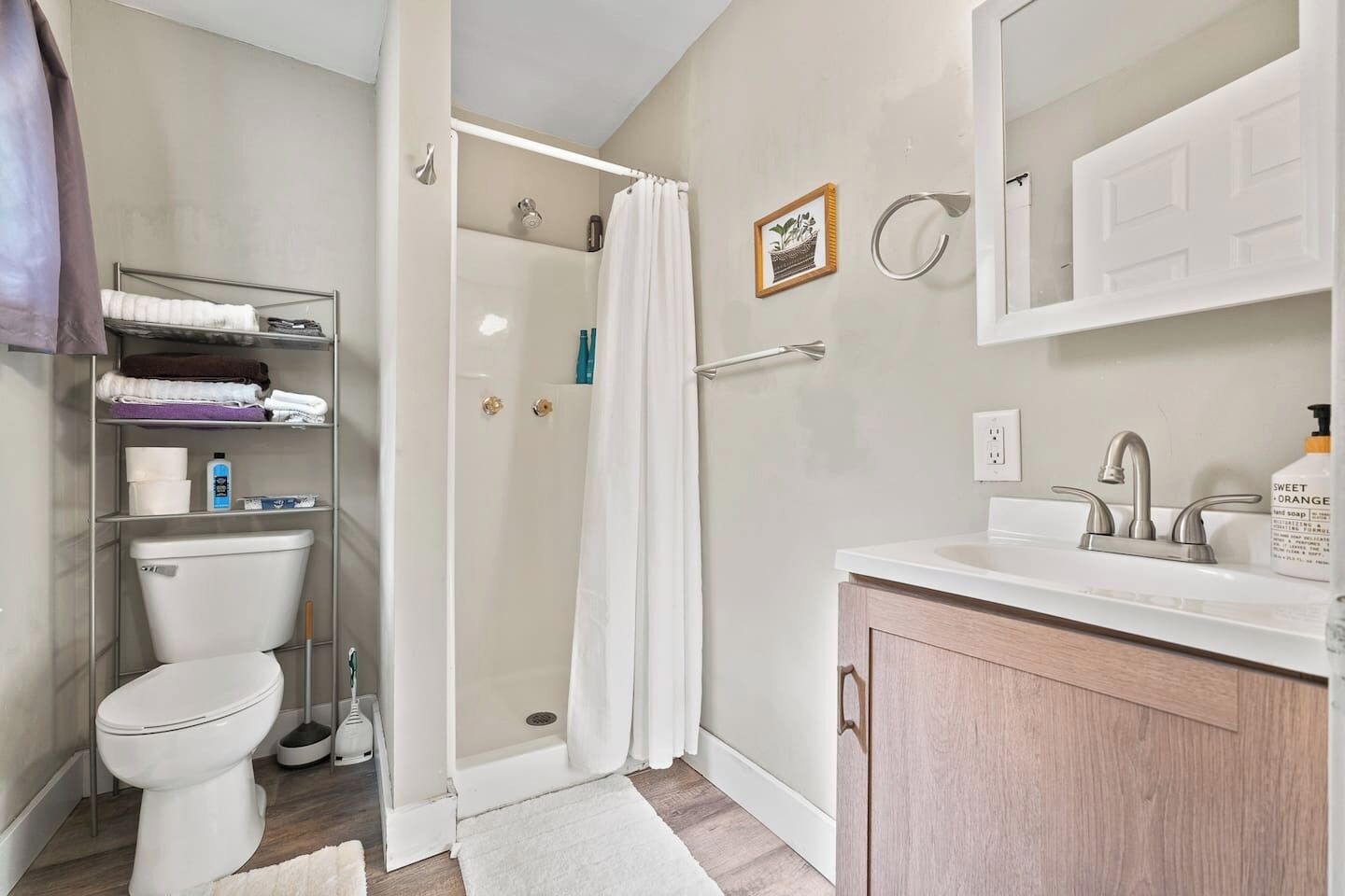 A bathroom with a toilet, shower, and sink.