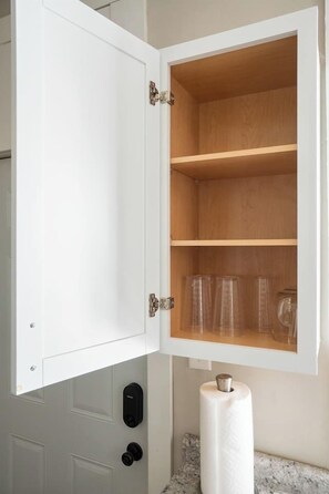 A white cabinet with a wooden interior, a black intercom, and a white toilet paper holder.