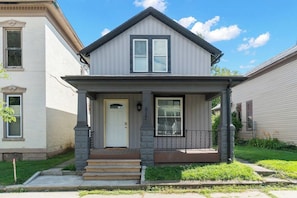 A two-story house with a front porch, a white door, and a number '517' on the wall. - Cozy 1BR Apartment | Pets Welcome, Central Location (Fort Wayne)