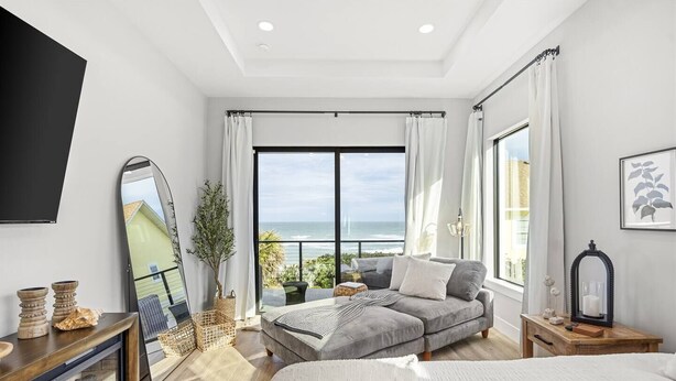 Een moderne slaapkamer met een groot bed, een bank en een balkon met uitzicht op zee.