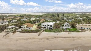 Een woongebied aan de kust met huizen in de buurt van het strand, met een zandstrand en uitzicht op zee.