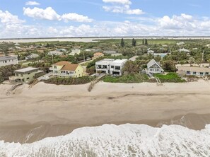 A coastal residential area with houses, a beach, and a view of the sea.