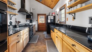 Een moderne keuken met houten kastjes, roestvrijstalen apparatuur en een zwart aanrecht.