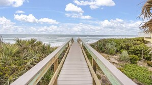 A wooden boardwalk leading to a beach with ocean views. - Beachfront Luxe Stay | Pool Access & Rooftop Deck with Stunning Views (Melbourne Beach)