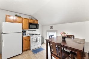 Una cocina con armarios de madera, un refrigerador blanco, una estufa y una mesa de comedor con sillas.