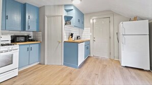 Een kleine keuken met blauwe kastjes, een witte koelkast en een houten aanrecht.