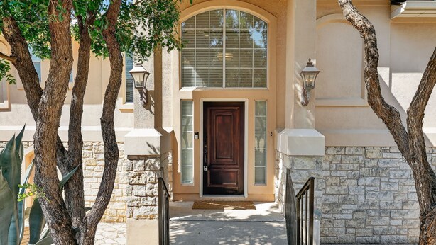 Une maison avec une façade en pierre, une grande fenêtre en arc de cercle et une porte en bois sombre.