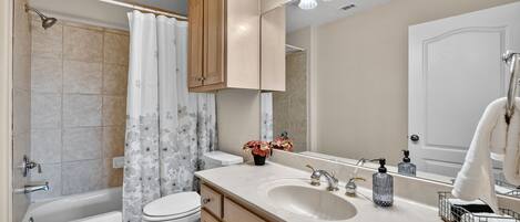 A bathroom with a bathtub, toilet, sink, and mirror.