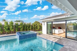 A modern house with a swimming pool, a hot tub, and a bedroom with a sliding glass door. - Luxe Haven with Poolside Lounge & Stunning Aquarium Floors (Scottsdale)
