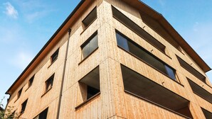 A multi-story building with a wooden facade and large windows. - Ferienwohnung mit Terrasse (Bürserberg)