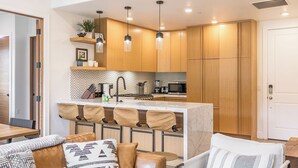 A modern kitchen with wooden cabinets, a marble island, and pendant lighting. - Slope Sight by Avantstay A+ Location w/ Hot Tub (Park City)