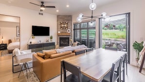 A modern living room with a sofa, a dining table, and a TV. - Slope Sight by Avantstay A+ Location w/ Hot Tub (Park City)