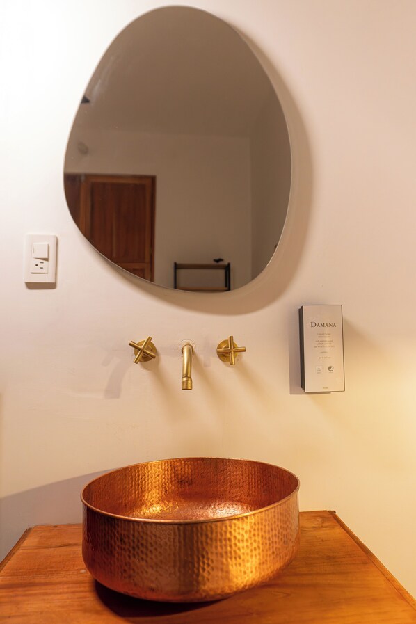 A bathroom with a copper sink, a round mirror, and a wall-mounted faucet. - TERRAKOTA Heritage House (San Sebastian de Mariquita)