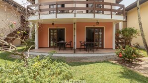 Edificio de dos pisos con un patio cubierto y mobiliario exterior.