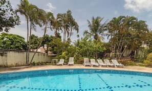 A swimming pool with lounge chairs and palm trees in the background. -  JSO | Conjunto de Apartamentos | Cond. Frente Mar (Porto Seguro)