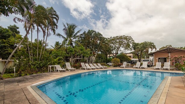 Una piscina con sillas de descanso y palmeras.