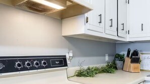 Una cocina con gabinetes blancos, una estufa y un bloque de cuchillos en la encimera.