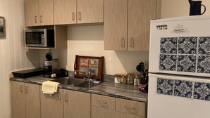 A kitchen with light wood cabinets, a stainless steel sink, a microwave, a refrigerator, and a coffee maker. - Miller House Carriage House Studio (mahone bay)