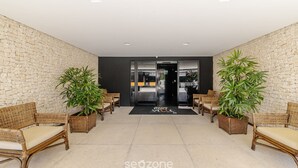 A lobby with wicker chairs, potted plants, and a stone wall. - Apts 600m From Ponta Verde Beach in Condo w/ Pool - RPV (Maceió)