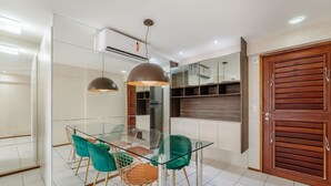A modern dining area with a glass table, green chairs, and pendant lights. - Apts 600m From Ponta Verde Beach in Condo w/ Pool - RPV (Maceió)