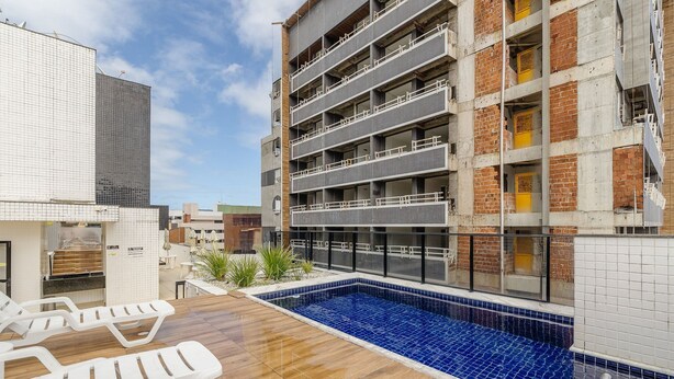 A rooftop pool area with lounge chairs, a blue mosaic pool, and a multi-story building with balconies. - Apts 600m From Ponta Verde Beach in Condo w/ Pool - RPV (Maceió)