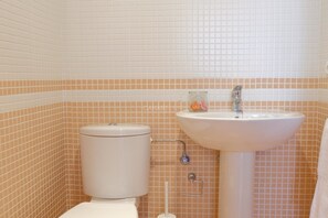 A bathroom with a toilet, sink, and tiled walls. - Palmar Breeze: stylish apt with pool view (Arona)