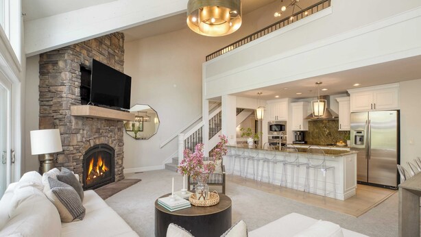 A spacious living area with a stone fireplace, a large flat-screen TV, and a modern kitchen with stainless steel appliances. - Deer Valley Delight by Avantstay Deer Valley Retreat + Spa (Park City)