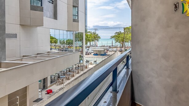 Ein modernes Gebäude mit einem Balkon mit Blick auf eine Strandbucht, ausgestattet mit Sitzgelegenheiten im Freien und Meerblick.