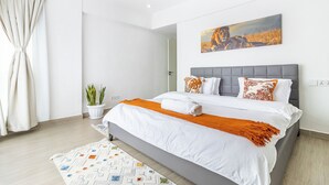 A modern bedroom with a large bed, a grey headboard, and a painting of a lion. - Elegant Apartment in Kilimani, Nairobi (Nairobi)