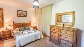 A bedroom with a wooden bed, bedside tables with lamps, a dresser, a window with a wooden frame, and a painting on the wall. - La Terrera Órgiva by Ruralidays (Granada)