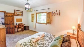 A bedroom with a bed, a wooden desk, a chair, a window with shutters, and a hanging light fixture. - La Terrera Órgiva by Ruralidays (Granada)