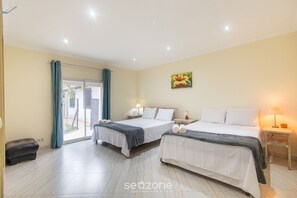 Hotelkamer met twee bedden, een raam met gordijnen, een schilderij aan de muur en een tafeltje met een lamp.