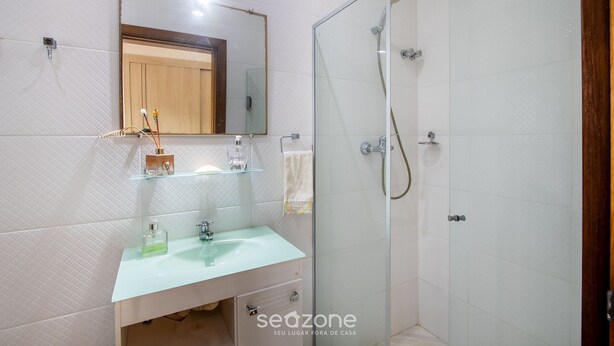 A bathroom with a glass shower enclosure, a sink with a mirror above it, and a towel hanging on the wall. - House w/ Pool 350 m From Taperapuan Beach Rud0047 (Porto Seguro)