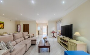 A living room with a sofa, a coffee table, a TV, and a lamp.