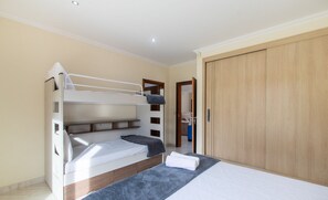 A bedroom with bunk beds, a wardrobe, and a bathroom visible through an open door.