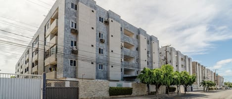 A multi-story residential building with a tiled facade, balconies, and a gated entrance.