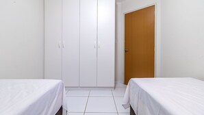 Ένα δωμάτιο με δύο κρεβάτια, μια ντουλάπα και μια πόρτα.