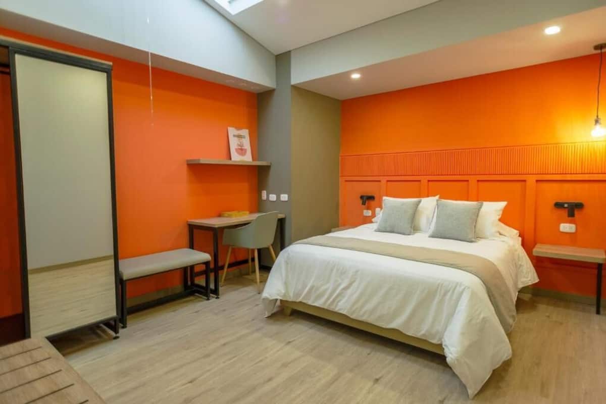 A bedroom with a bed, bedside tables, a desk, and a chair.