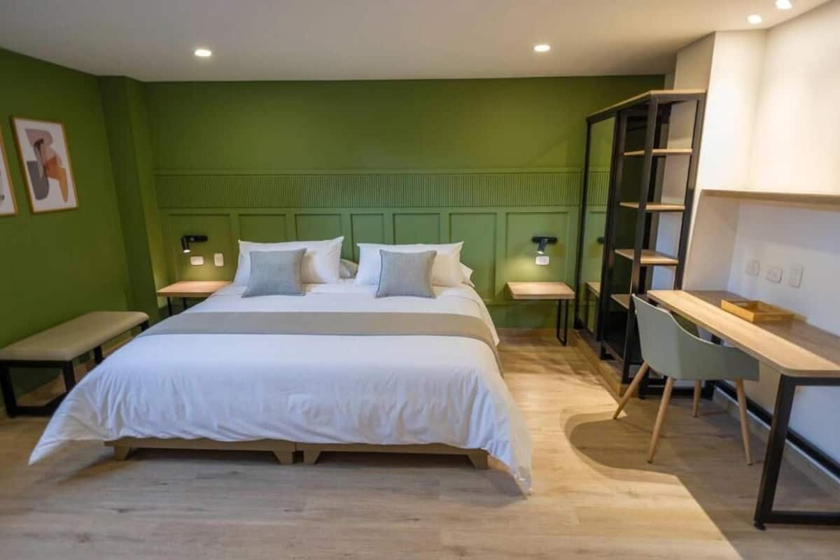 A bedroom with a large bed, bedside tables, a desk, and a chair.