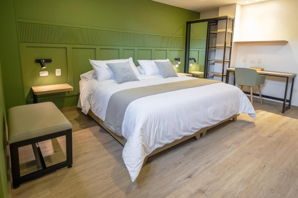 A neatly arranged bedroom with a large bed, bedside tables, a desk, and a chair.
