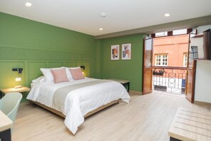 Une chambre à coucher comprenant un lit, des tables de chevet, une chaise et un balcon avec une balustrade.