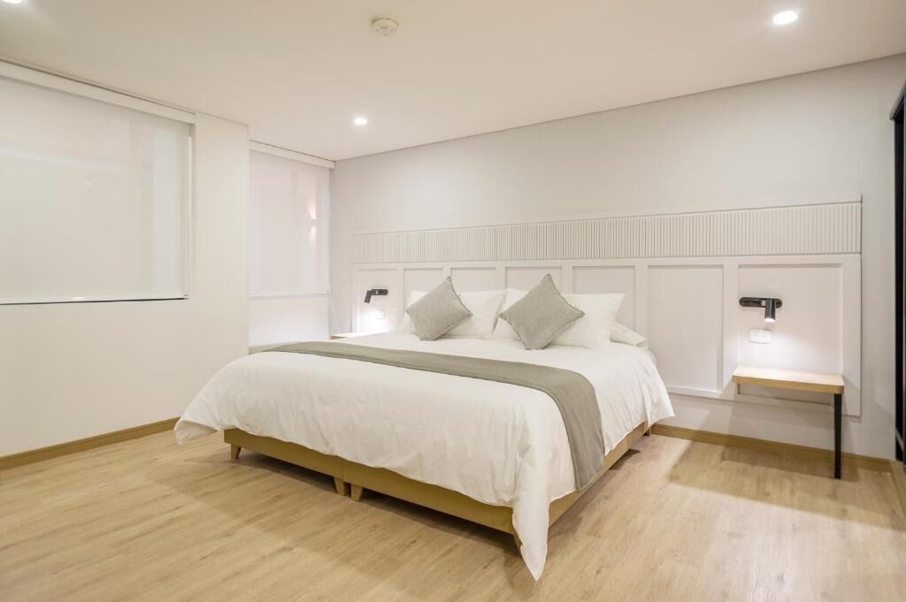 Een moderne slaapkamer met een bed, nachtkastjes en een hoofdbord.