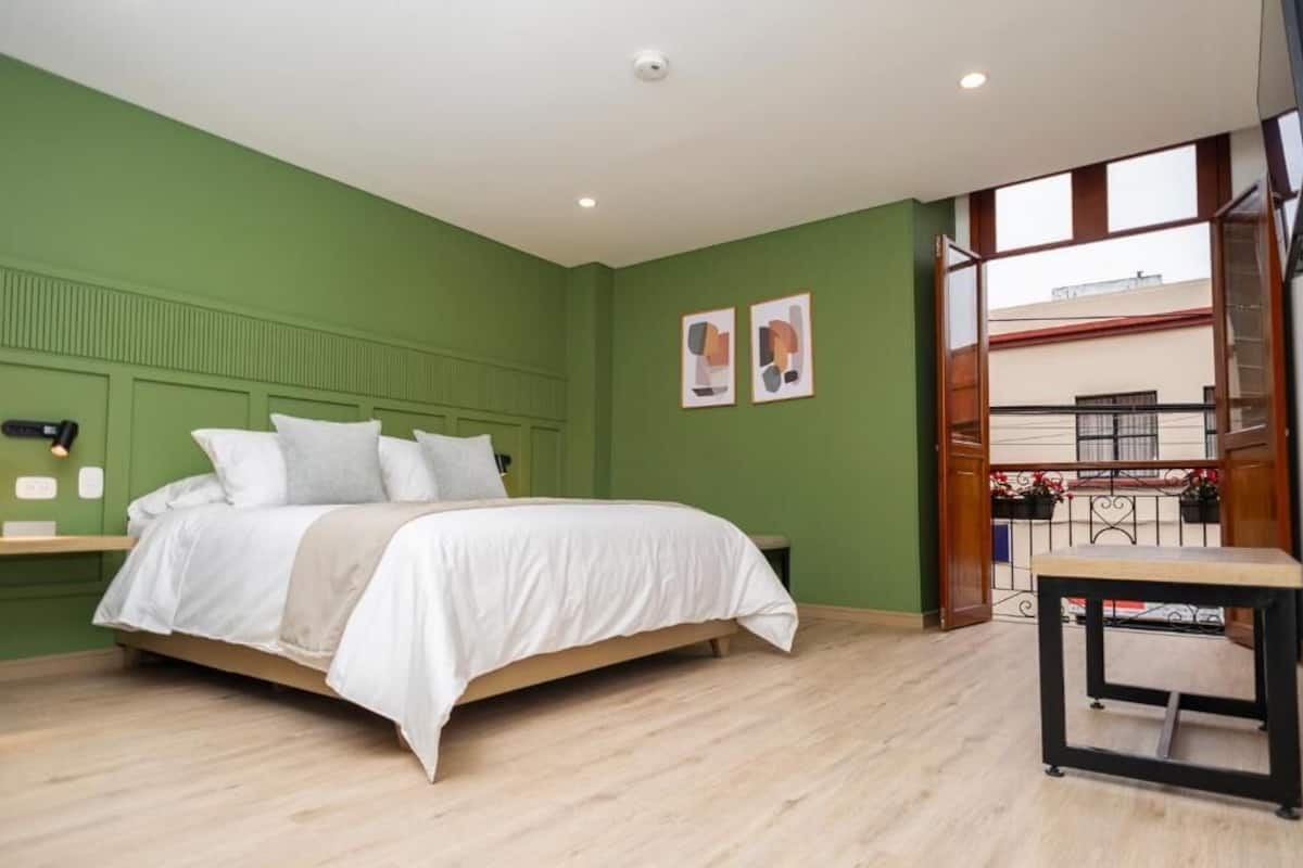 A bedroom with a bed, a small table, and a view of the outside balcony.