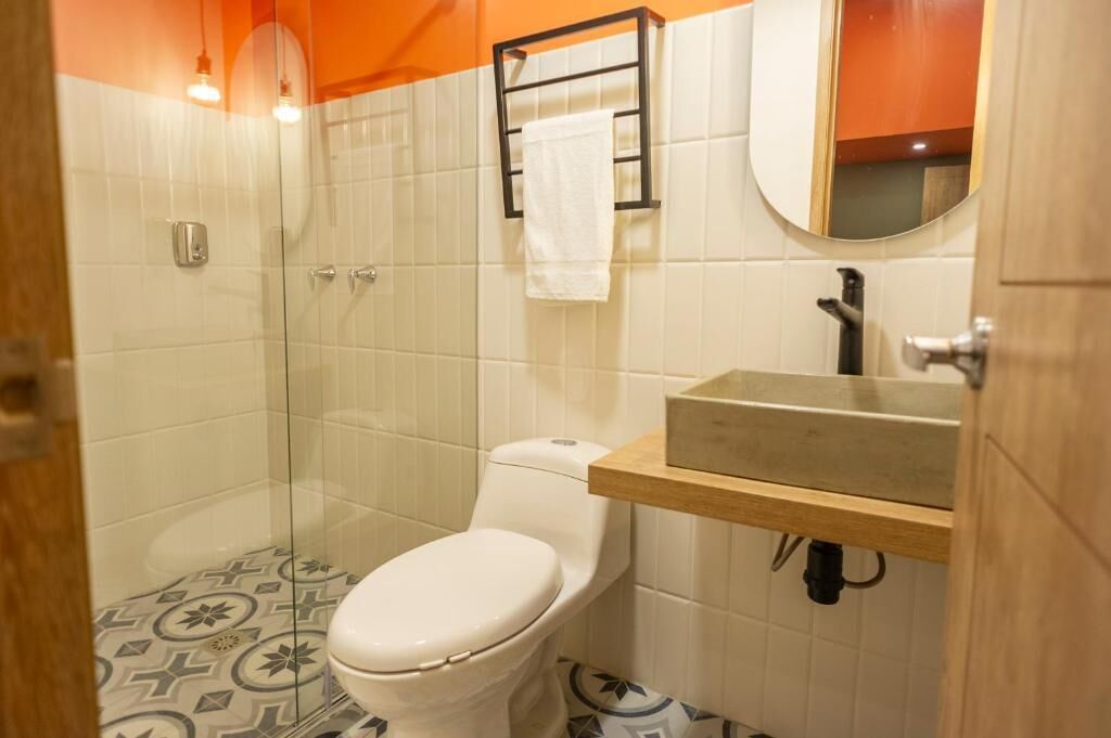 A bathroom with a toilet, a glass shower enclosure, a sink with a mirror, and a towel rack.