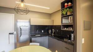 A modern kitchen with a stainless steel refrigerator, a black countertop, and a white dining table. - Apt With Pool 200m From the Beach Skc0414 (Maceió)