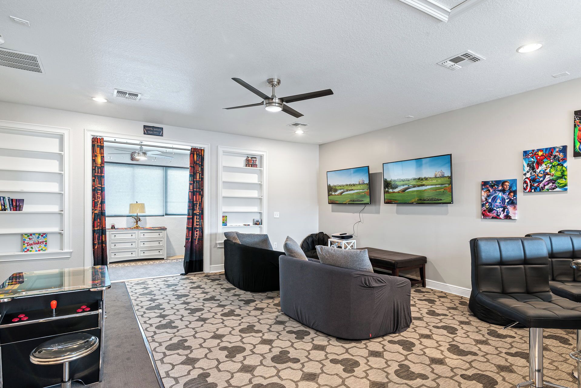 A modern living room with a ceiling fan, a flat-screen TV, and a large window with curtains.