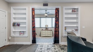 A living room with a sofa, a coffee table, and a bookshelf. There is a door leading to another room. - Inviting 5BR Villa in Reunion Resort (Kissimmee)