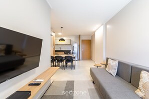 Ein modernes Wohnzimmer mit Flachbildfernseher, einer Couch und einem Essbereich mit Stühlen und einem Tisch.